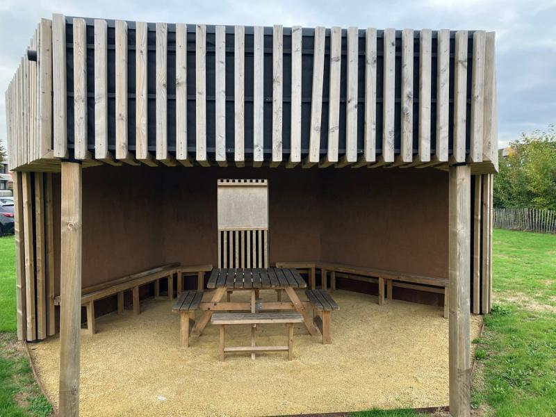 Refugio de madera con mesas de picnic en una zona de huertos de ocio