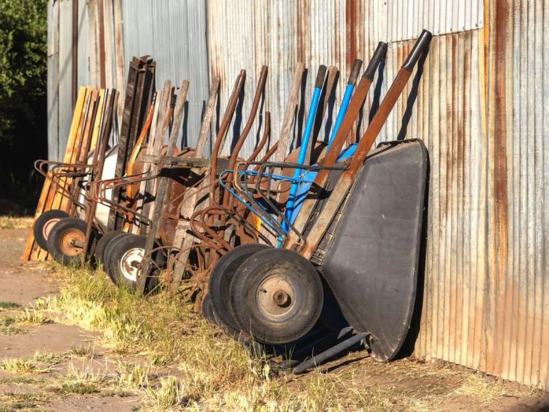 Carretillas antiguas junto a una pared rústica en un huerto de San Andrés del Rabanedo