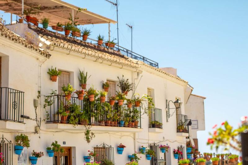 Balcón soleado lleno de macetas en un pueblo español